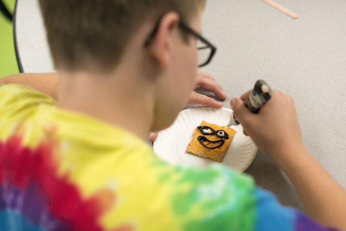 Boy decorating pumpkin cookie