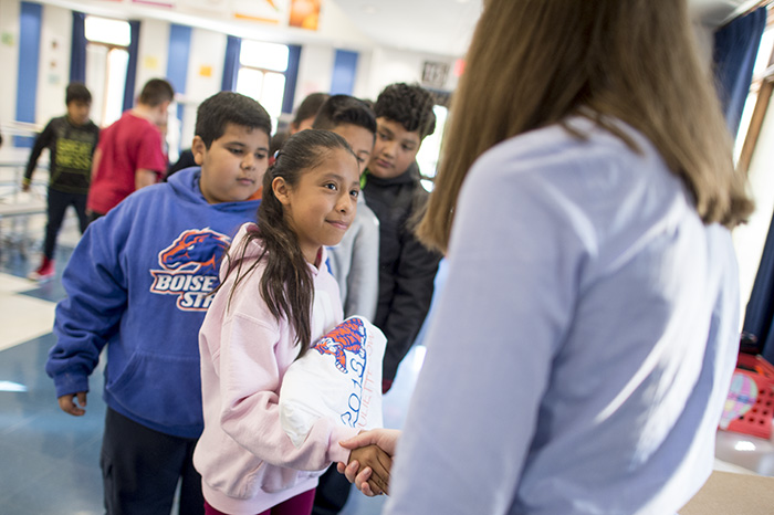 Students shaking hands with tshirt in hand