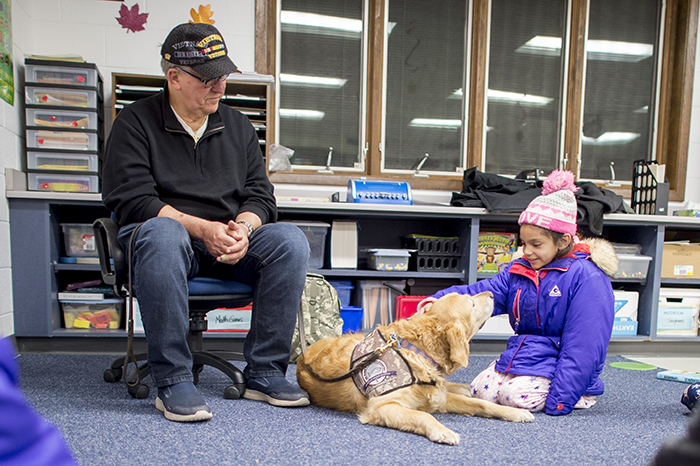 Girl petting dog with volunteer sitting